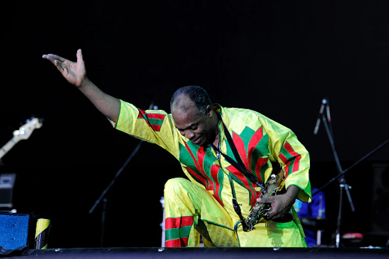 A man taking a bow on stage while holding a saxophone
