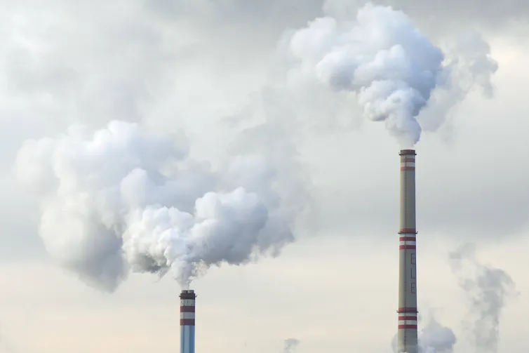 Plumes billow from two industrial stacks.