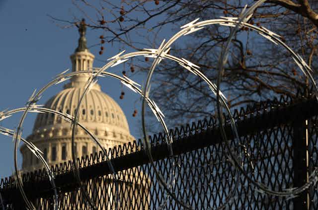 The US Capitol dome, behind a security fence topped with razor wire