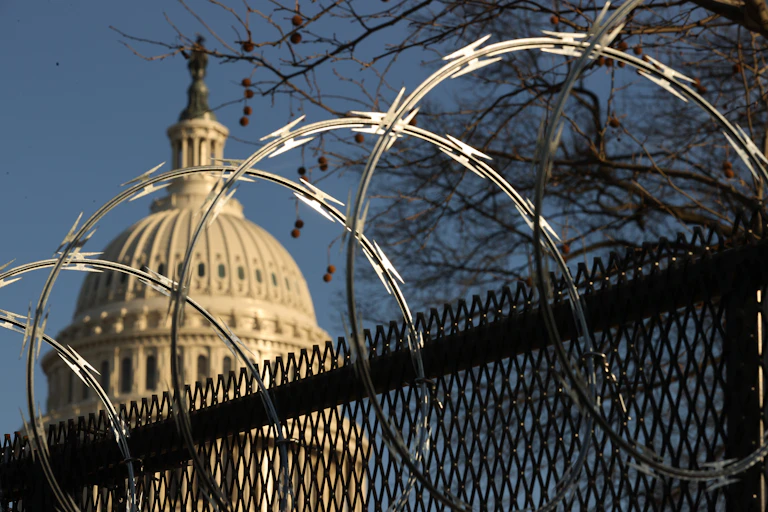 The US Capitol dome, behind a security fence topped with razor wire