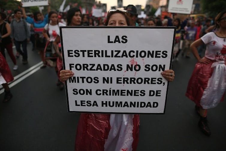 Peruvian protester holds a sign reading, 'Forced sterilizations are not myths or errors; they are crimes against humanity.'