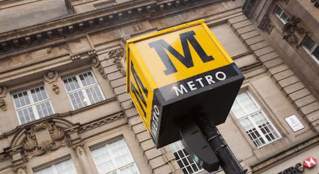 Yellow metro sign in front of city building