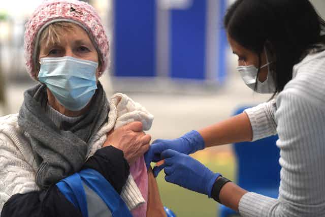 A woman in a mask being vaccinated