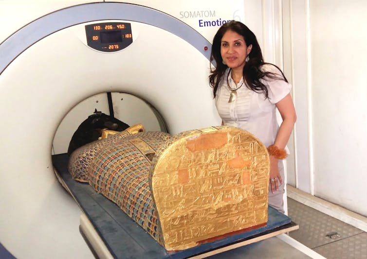 The mummy going into the CT scanner, with lead author Sahar Saleem next to it.