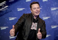 Elon Musk's left and right hands express a thumbs up gesture.