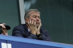 Roman Abramovich rests his hands on his face as he watches his Chelsea soccer team play.