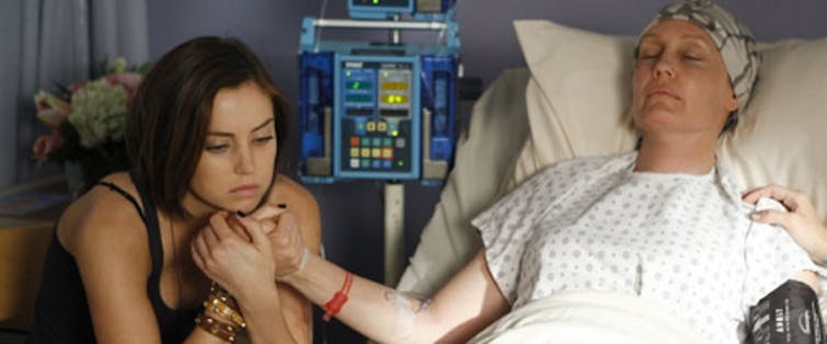 Teen sits next to her mother's hospital bed.