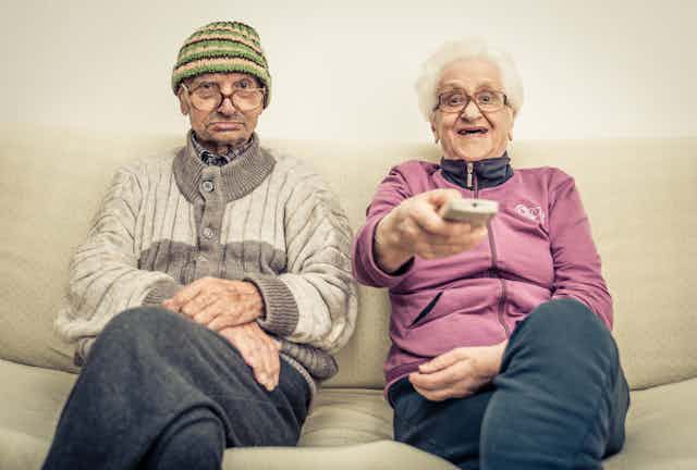 old couple watching television on the couch 