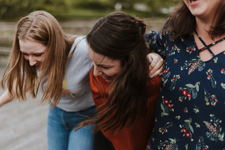 Three female friends with their hands around each other.