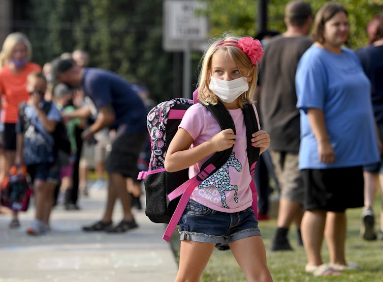 Children head to school past adults not wearing masks
