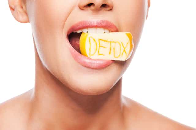 Rostro de una mujer con un trozo de manzana con la inscripción detox en la boca 