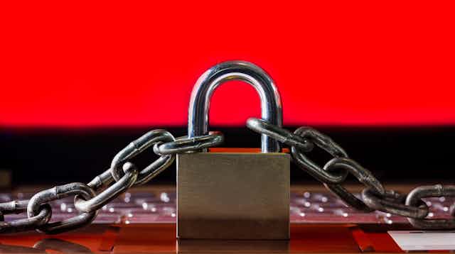 A padlock and chain against a red background on a laptop keyboard