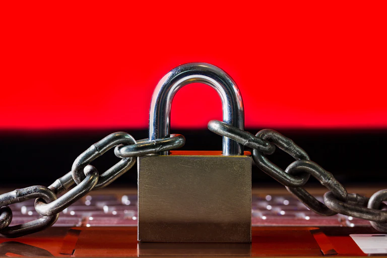 A padlock and chain against a red background on a laptop keyboard