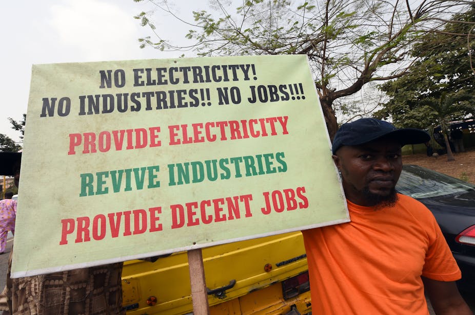 A man holds a placard reading 'No electricity! No industries!! No jobs!!! Provide electricity, revive industries, provide decent jobs'