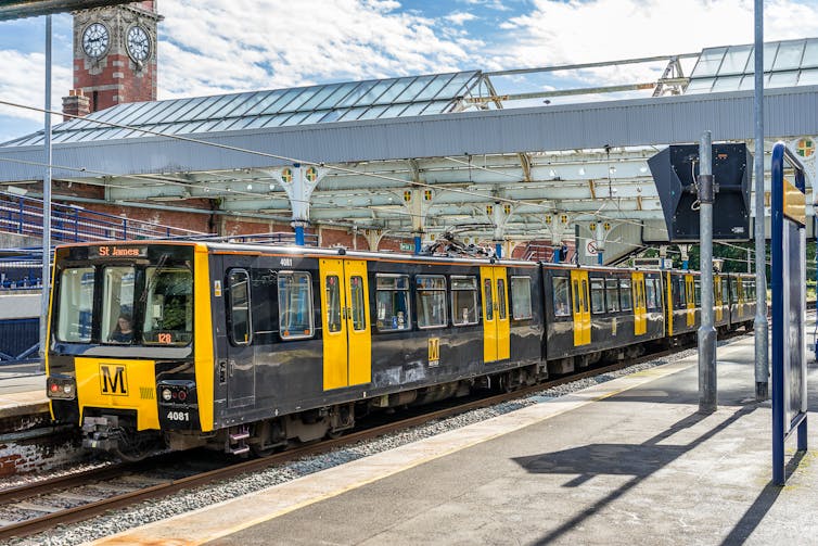 Yellow and black light rail train in station.