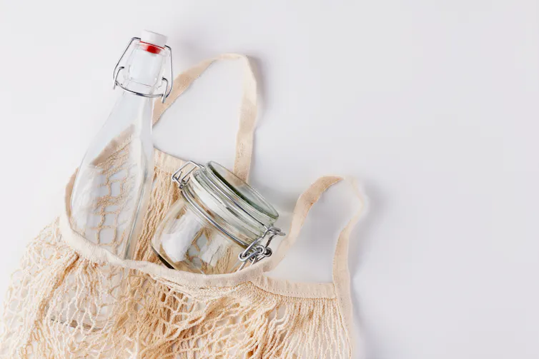 A fabric bag filled with a glass bottle and mason jar.