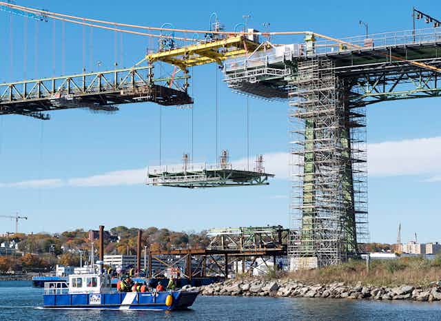 Workers lift a new portion of a bridge.