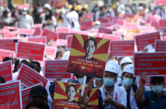 A protester holds up a placard with an image of deposed Myanmar leader Aung San Suu Kyi during an anti-coup rally with many signs seen in the background. 