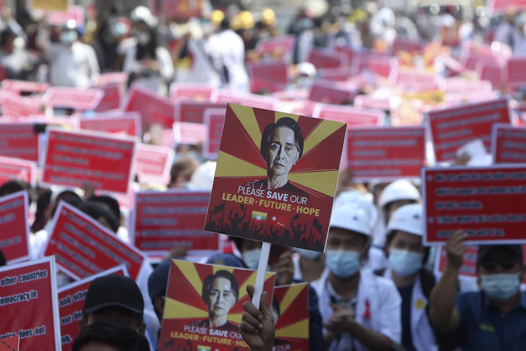 A protester holds up a placard with an image of deposed Myanmar leader Aung San Suu Kyi during an anti-coup rally with many signs seen in the background.