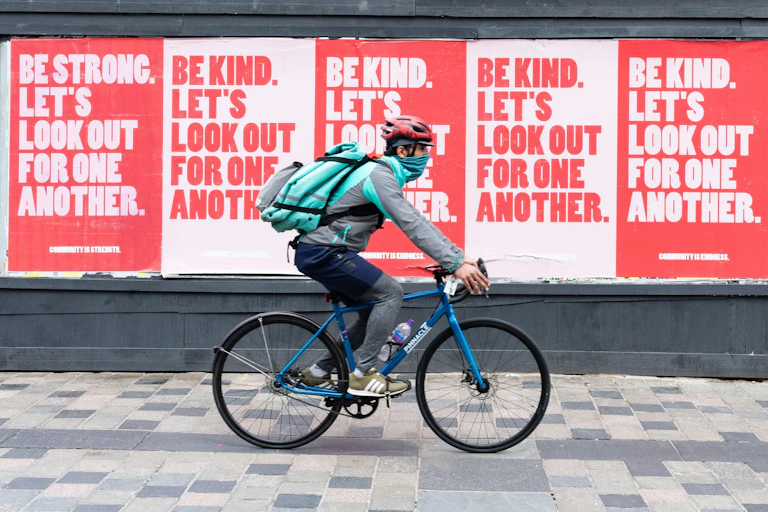 A man rides a bicycle past posters.