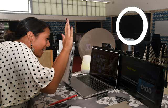 A teacher waves 'hello' to her online class.
