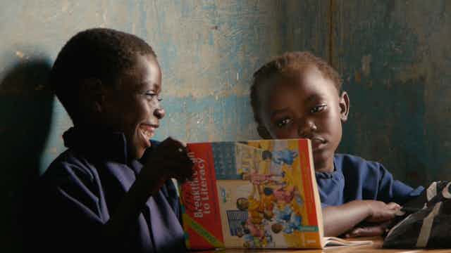 Two children looking at an English textbook