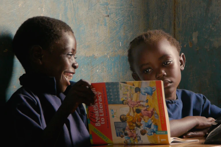 Two children looking at an English textbook