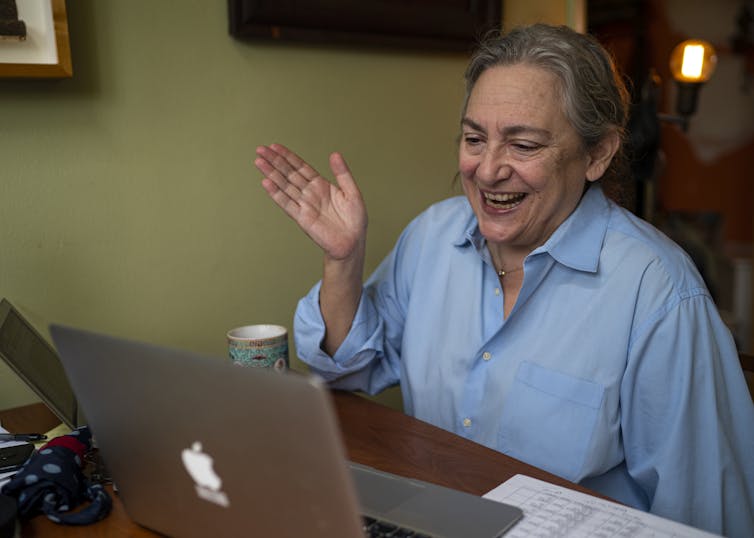 A woman smiles while looking at her laptop.