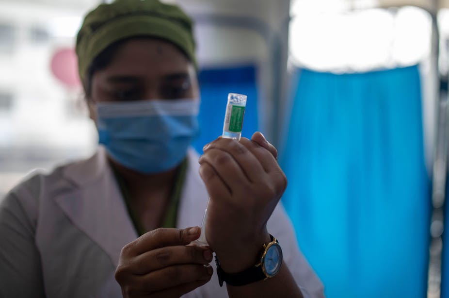 Nurse with mask on prepares coronavirus vaccine.