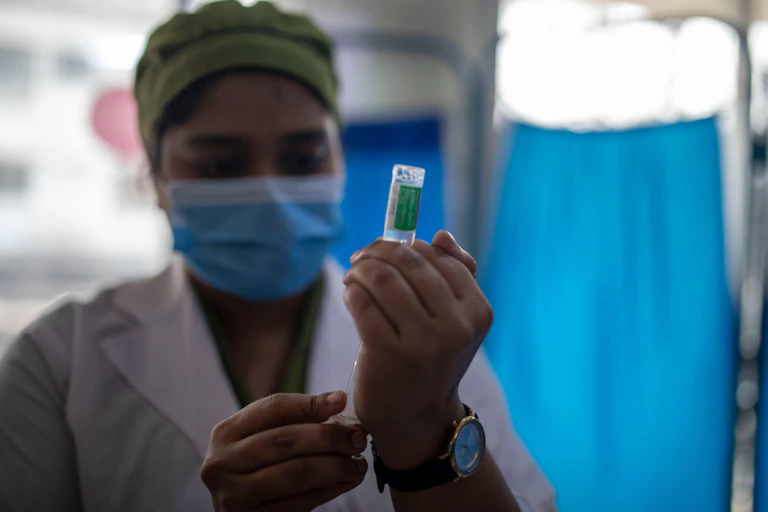 Nurse with mask on prepares coronavirus vaccine.