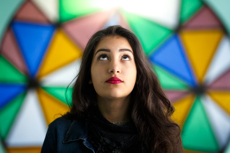A woman looks upward in front of a stained-glass window