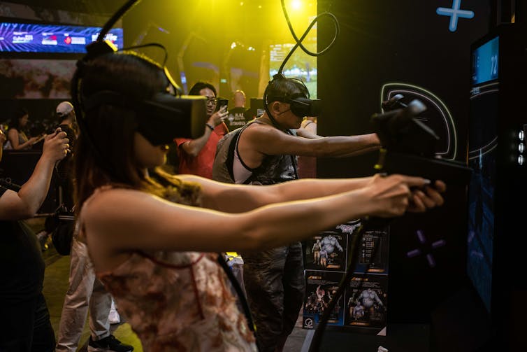 A young woman uses a VR headset an a console while playing a video game.