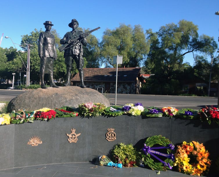 A statue of two soldiers, surrounded by wreaths.