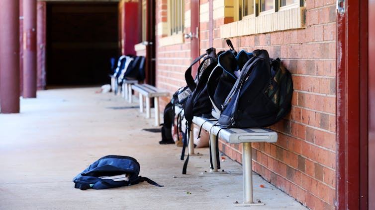 School bags on benches outside a classroom.