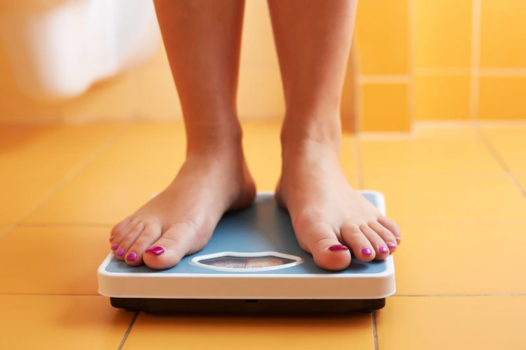 Woman standing on bathroom scale.