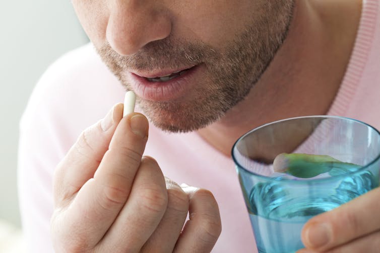 Man taking medication with glass of water.
