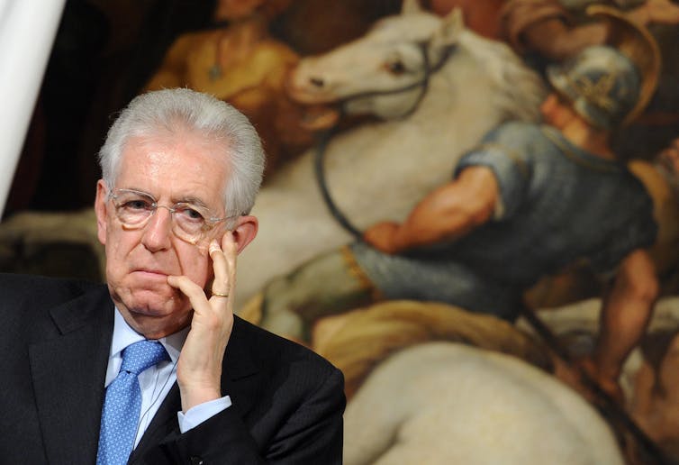 Mario Monti sitting in front of a painting in Rome.