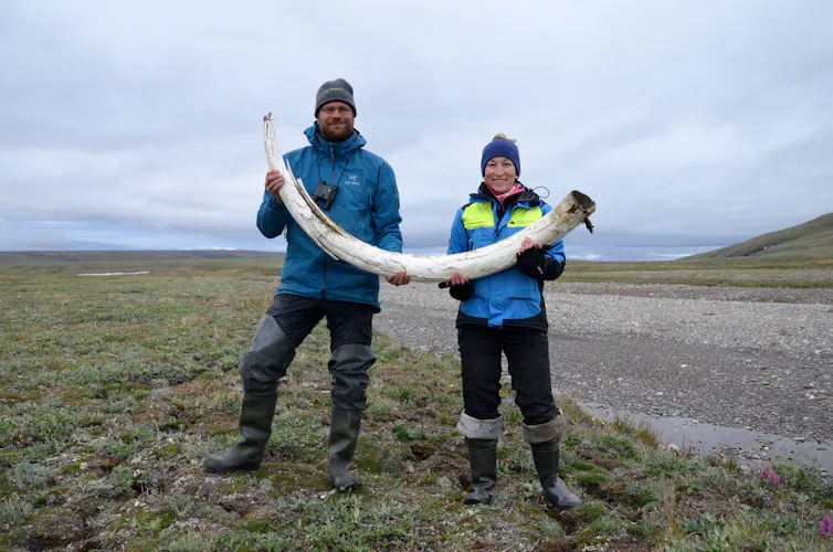 Two of the study authors holding a mammoth tusk.