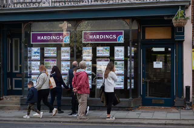 People gather outside looking at an estate agent's window