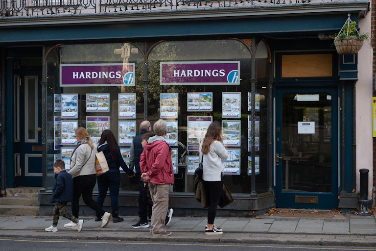 People gather outside looking at an estate agent's window