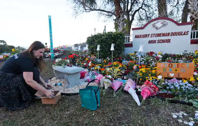 A woman places items at a memorial