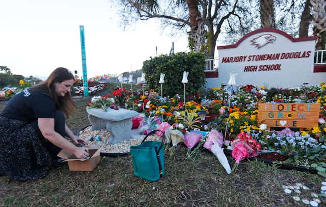 A woman places items at a memorial