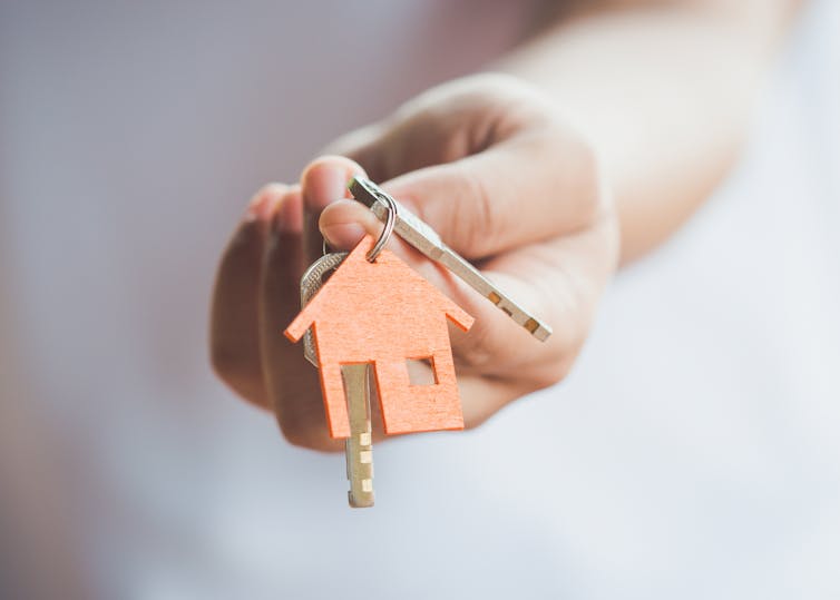 Hand holds out keys with a house-shaped keyring