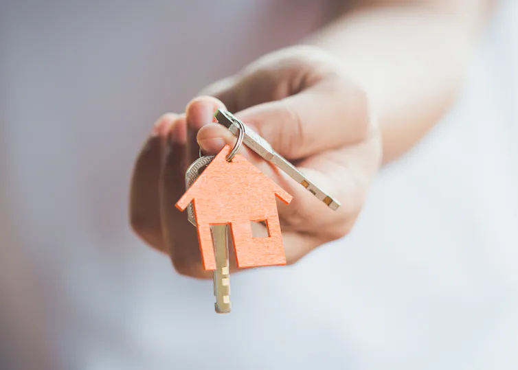 Hand holds out keys with a house-shaped keyring
