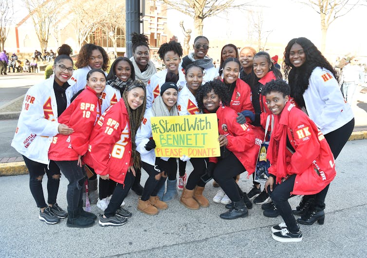 A group of young African American women hold a sign that reads #StandWithBennet