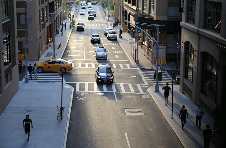 People walking down a city street with cars.