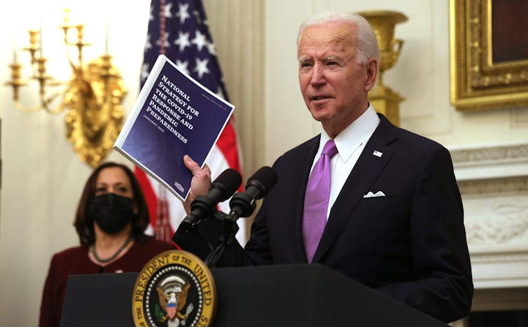 Joe Biden holds a copy of the national COVID-19 strategy