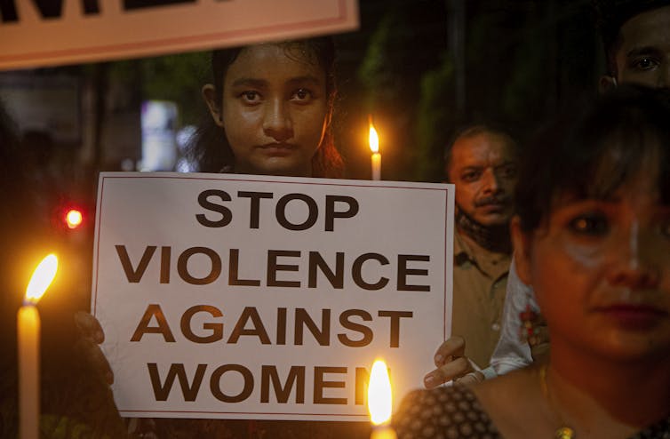 Uma mulher carrega um cartaz que diz 'Acabar com a violência contra as mulheres'.