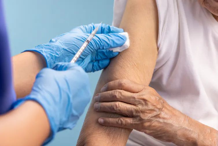Nurse giving vaccine to elderly person