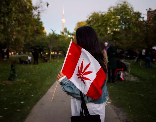 A woman carrying a flag with a cannabis leaf instead of a maple leaf